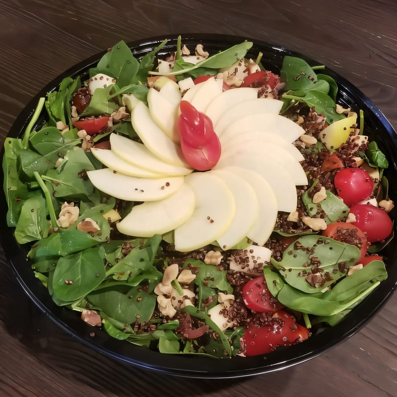 Sprout Mediterranean salad with spinach, quinoa, tomatoes, apples, and nuts in a black bowl.